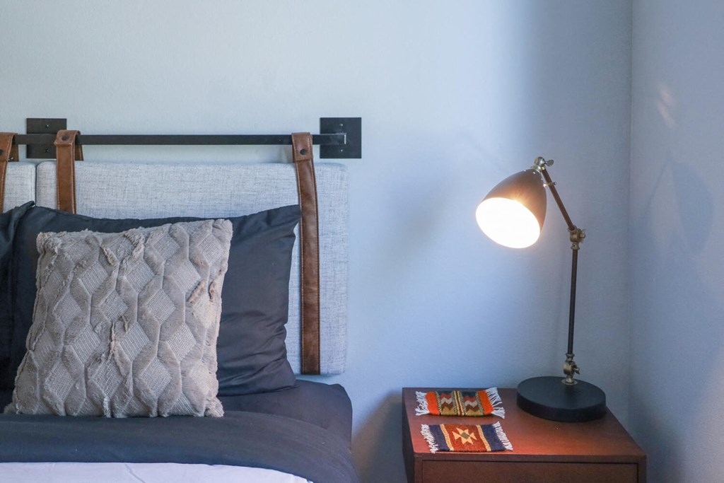 a bedroom with a bed and a nightstand with a lamp