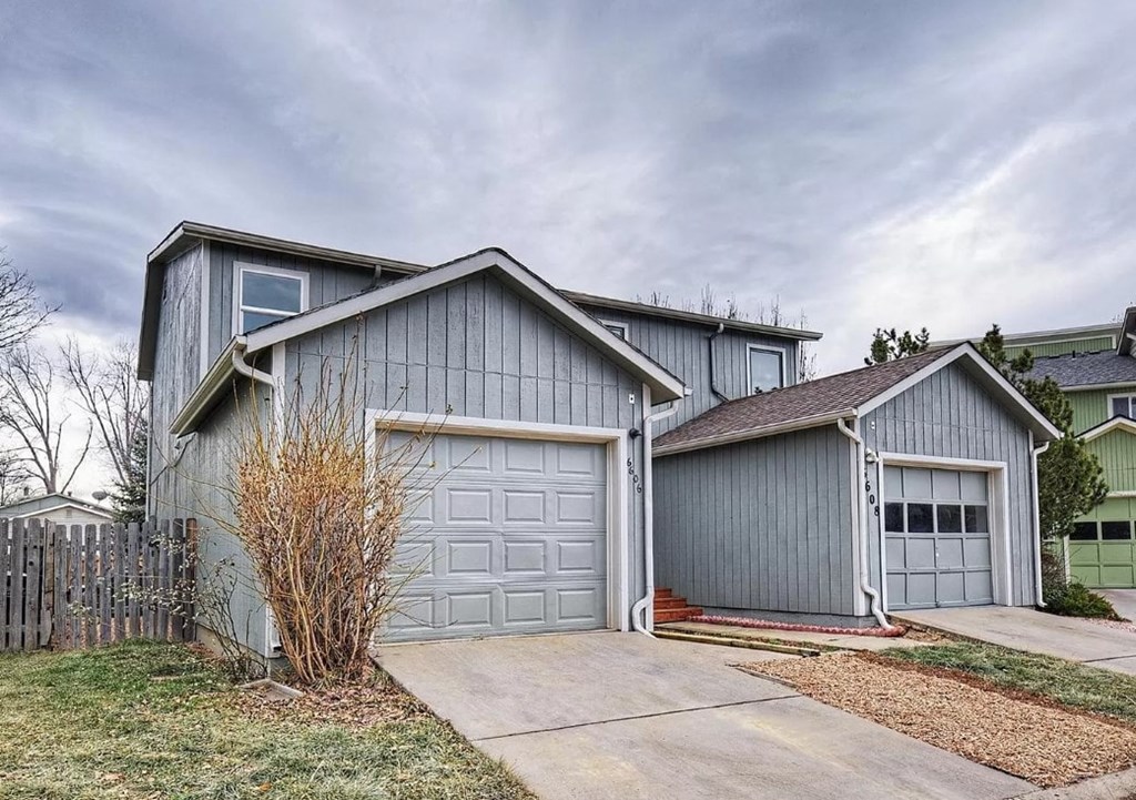 a blue house with two garage doors and a driveway