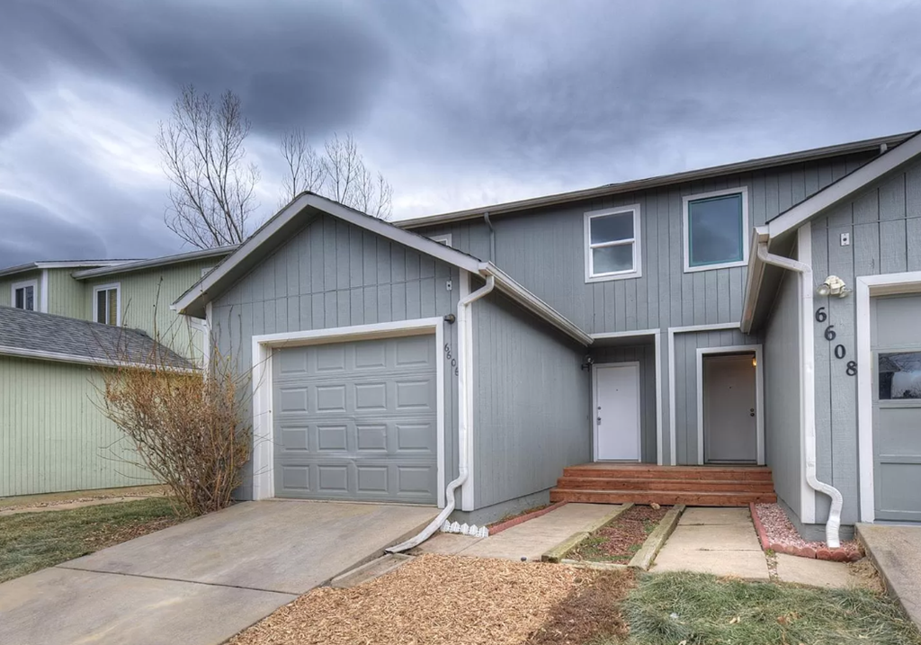 a blue house with a garage and a cloudy sky