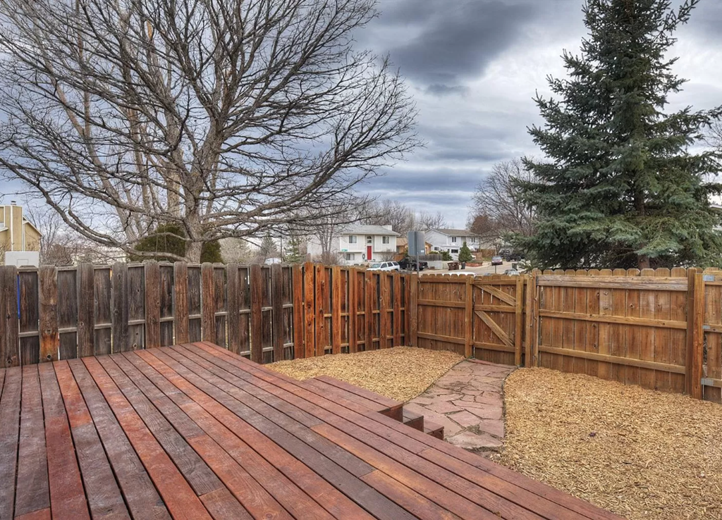 a backyard with a wooden deck and a wooden fence