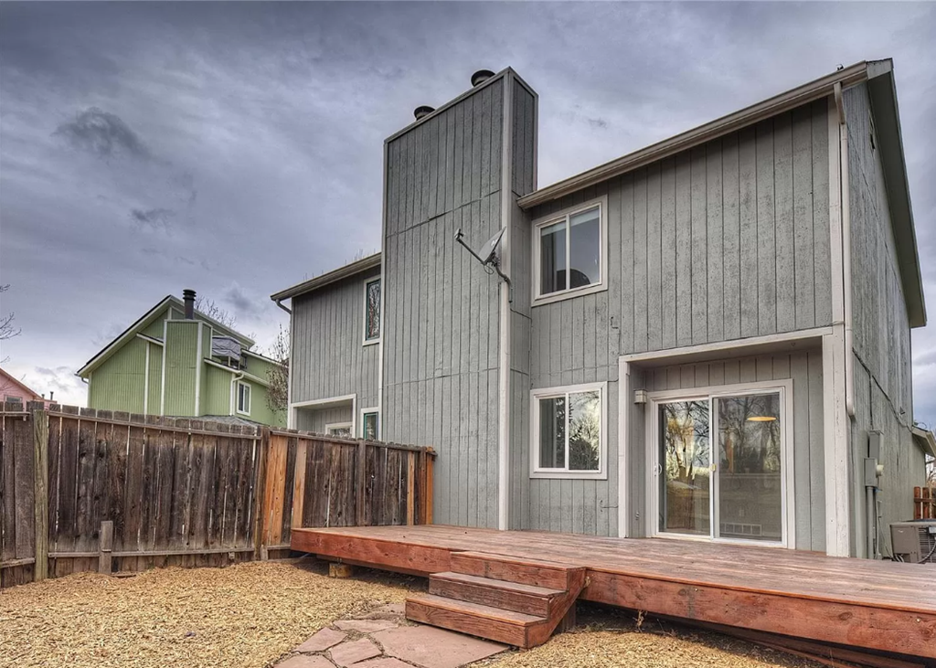 a home with a wooden deck and a wooden fence