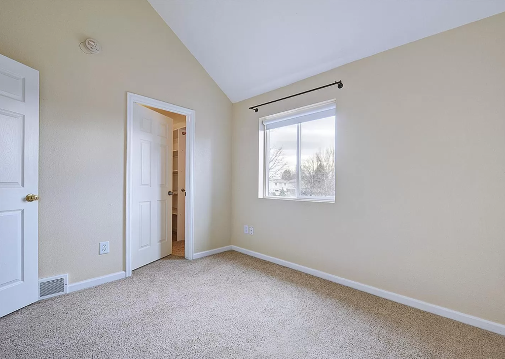 an empty bedroom with a window and a door