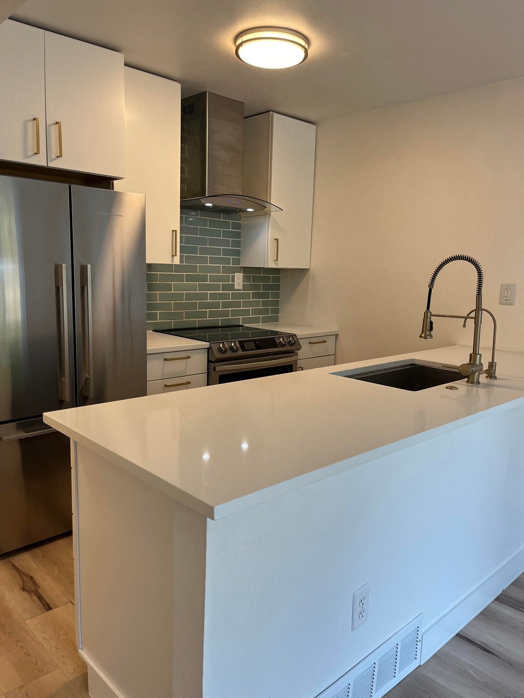 a kitchen with a white counter top and a stainless steel refrigerator