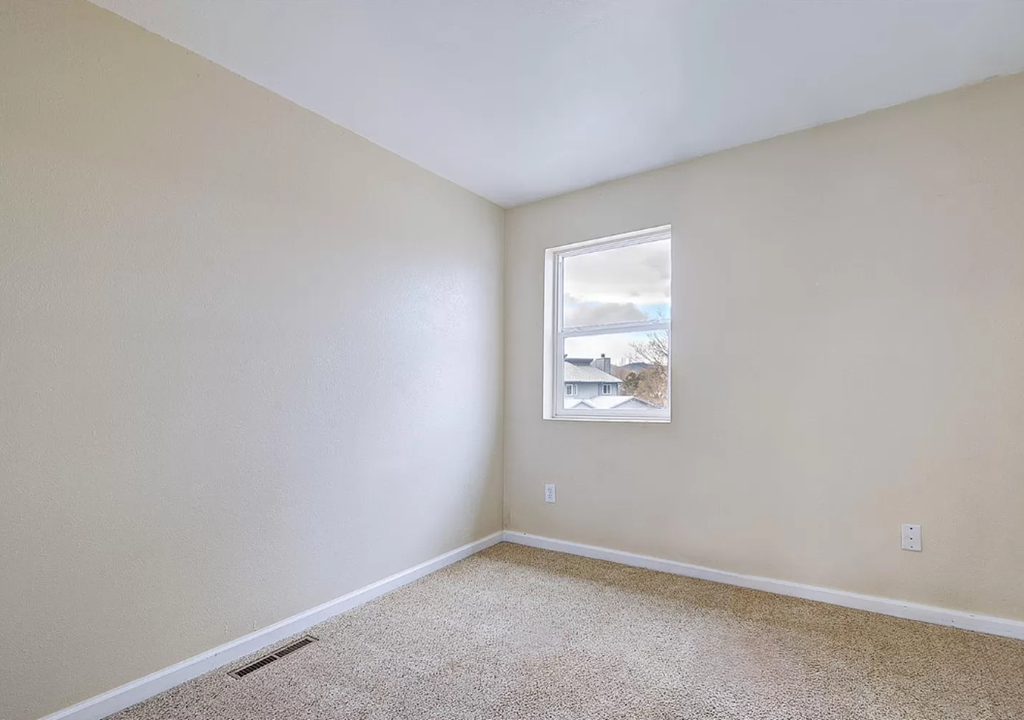 an empty room with a window and carpet