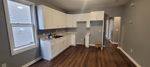 A kitchen with white cabinets and a wooden floor.
