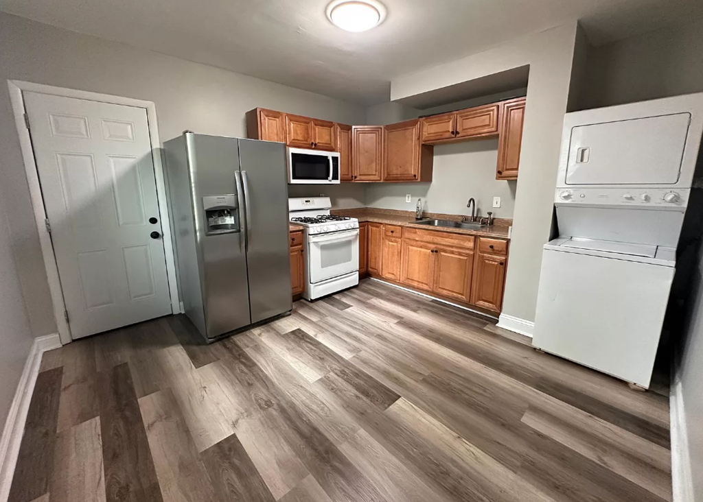 a kitchen with wooden floors and a stainless steel refrigerator