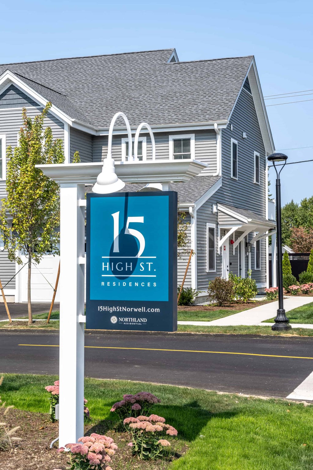a sign in front of a house with a house in the background