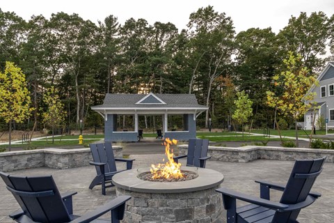 a fire pit with chairs around it and a gazebo in the background