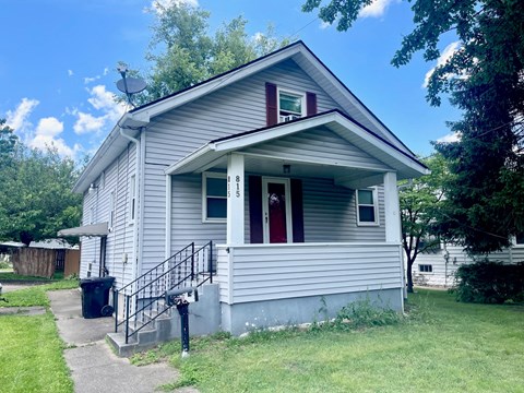 a small white house with a porch and a staircase