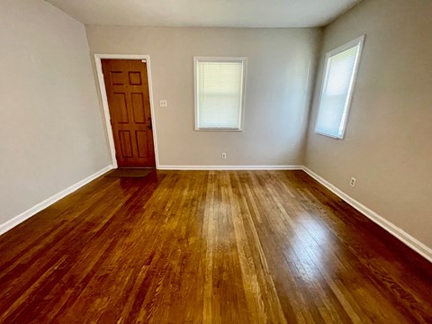 an empty living room with wooden floors and a door