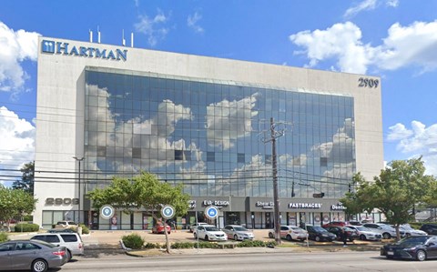 an office building with clouds reflected in the windows