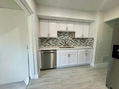 a small kitchen with white cabinets and a stainless steel dishwasher