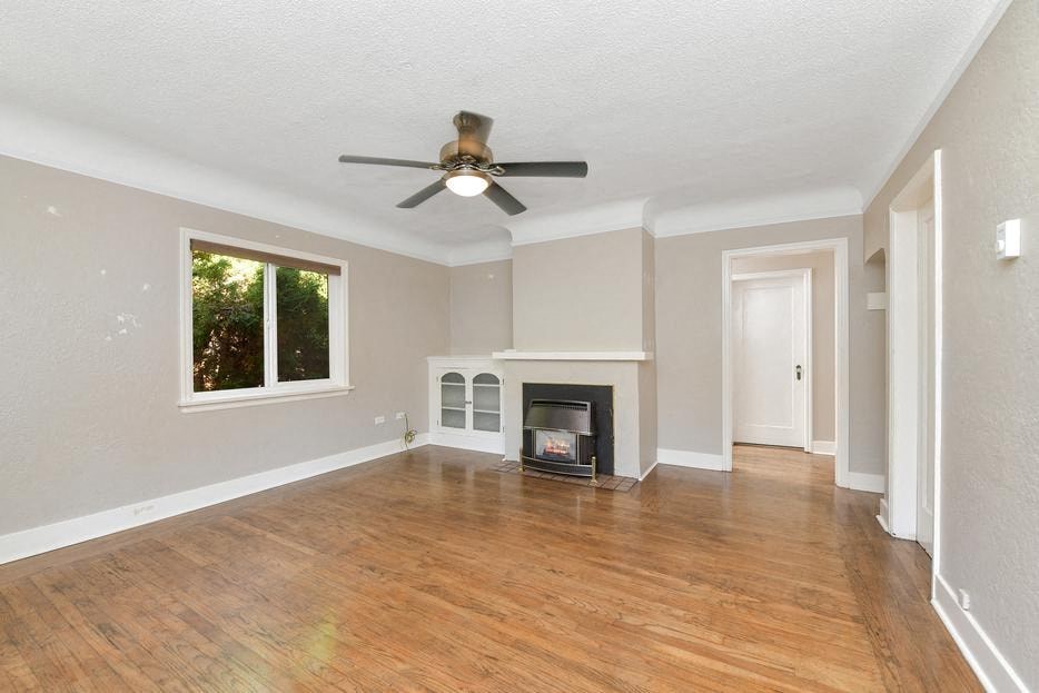 an empty living room with a ceiling fan and a fireplace
