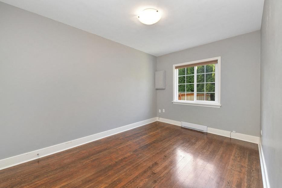 an empty living room with wood floors and a window