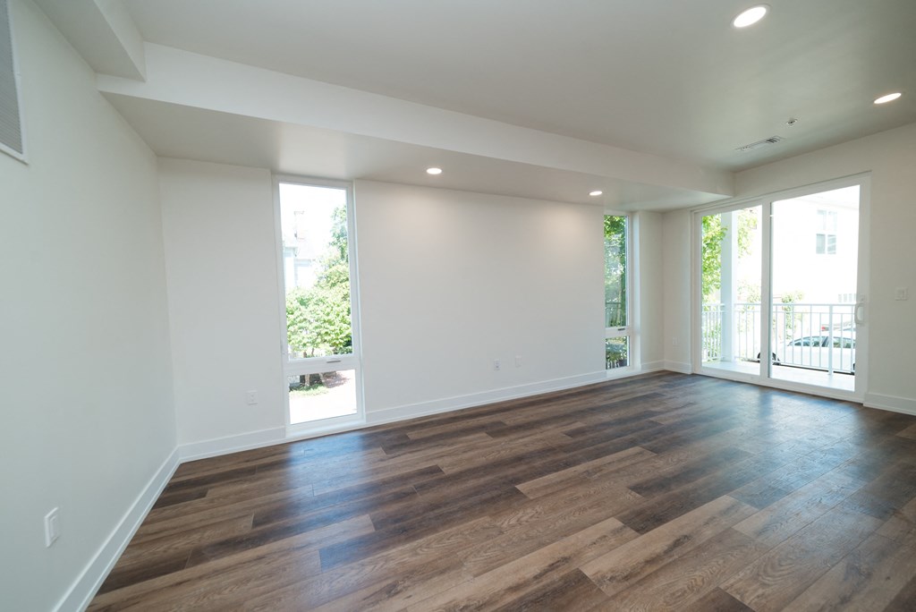 an empty living room with wood flooring and a balcony