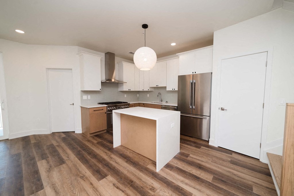 a kitchen with a white island and a stainless steel refrigerator