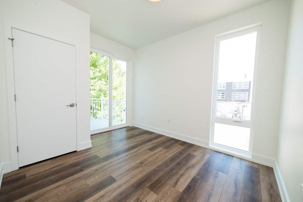 a living room with wood floors and a door to a balcony