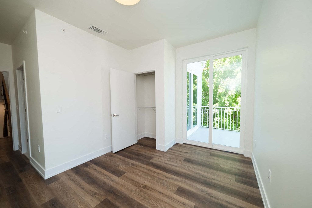 a living room with white walls and a large window and wooden floors