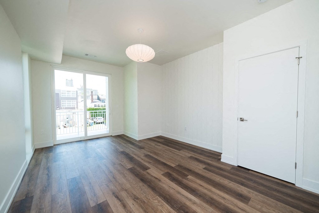 a living room with white walls and a door to a balcony
