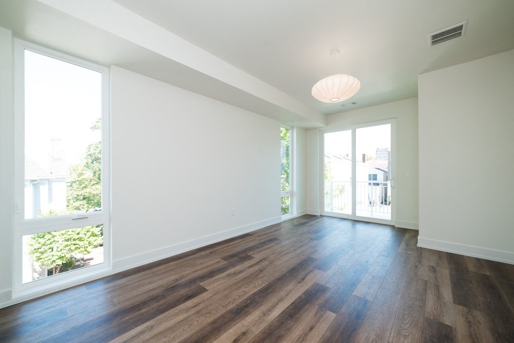 an empty living room with wood flooring and large windows