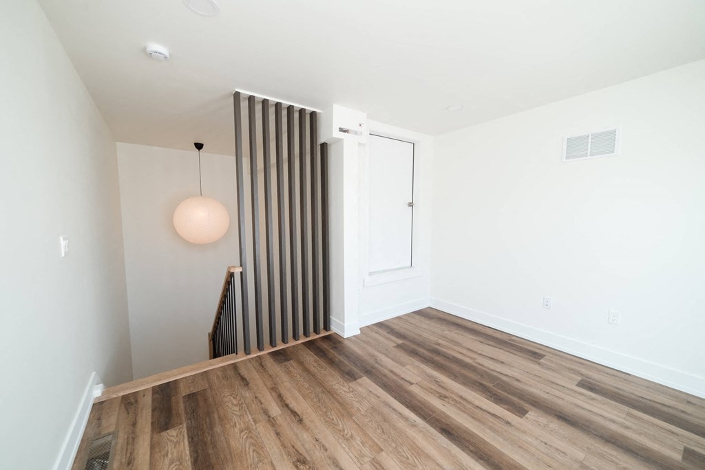 a living room with wood floors and white walls and a staircase
