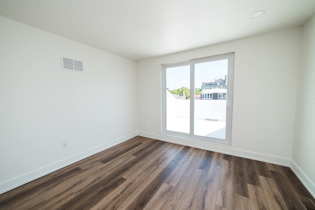 a living room with a large window and wooden floors