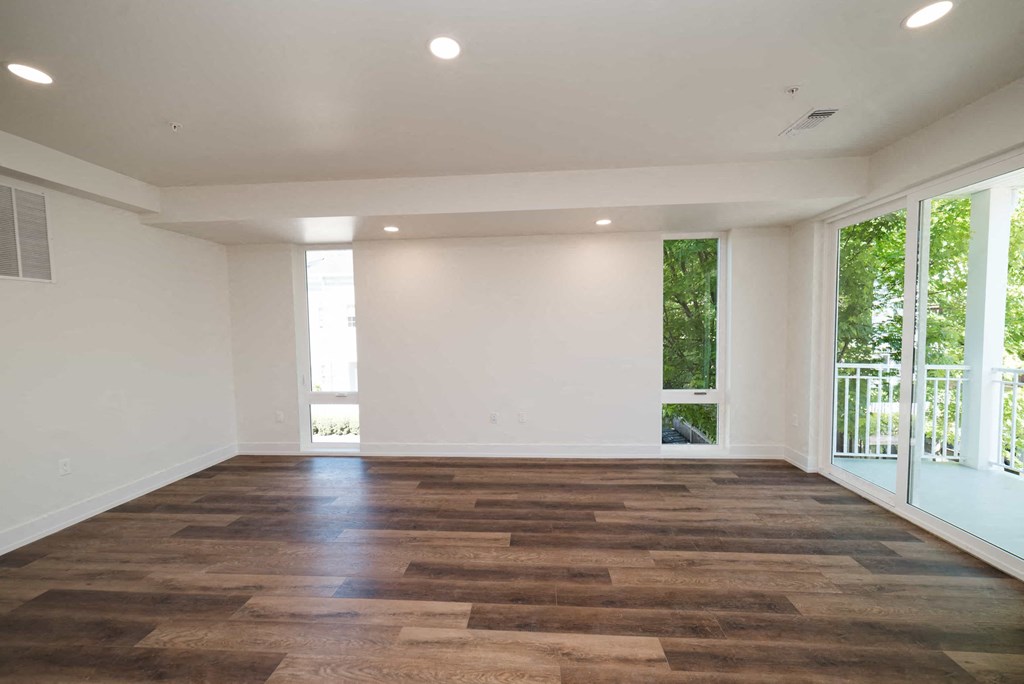 an empty living room with wood flooring and a balcony