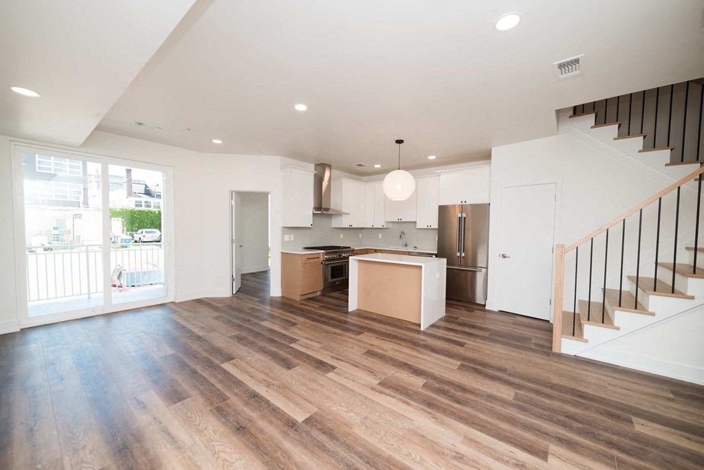 a living room with a staircase and a kitchen in a house