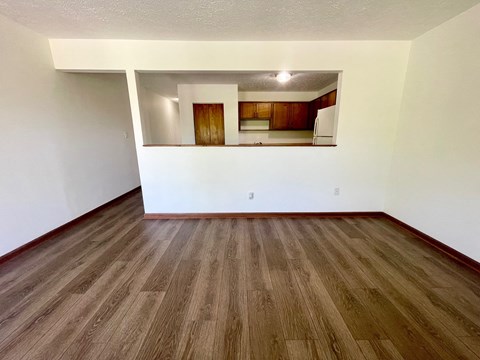 the living room of an empty apartment with wood flooring and white walls