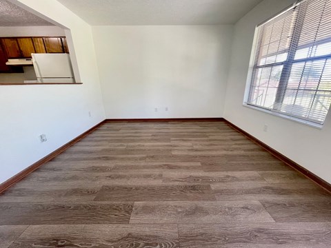 an empty living room with wood flooring and a window