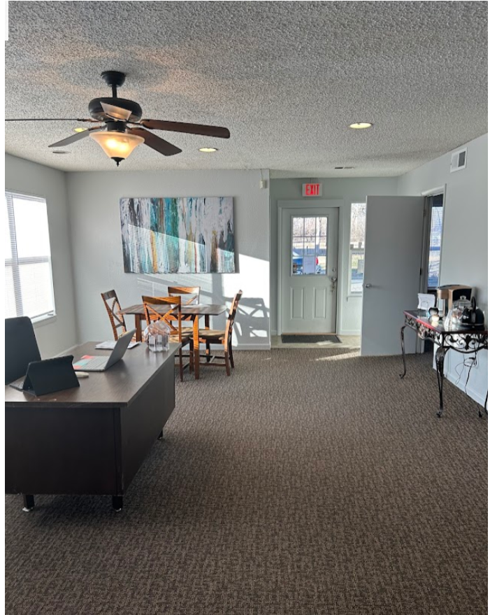 a living room with a desk and a ceiling fan