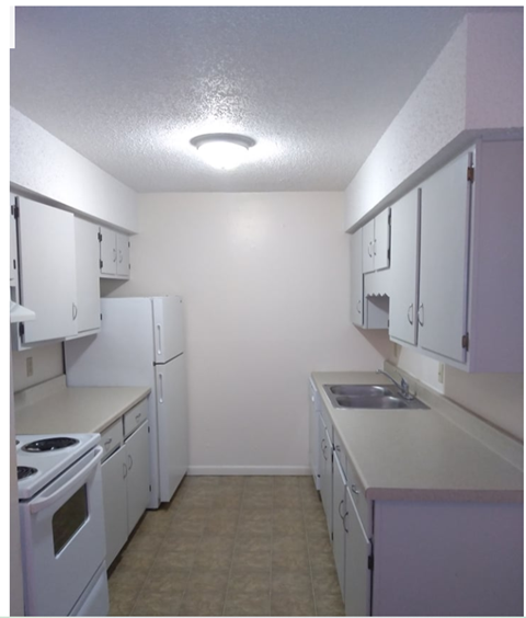 an empty kitchen with white appliances and white cabinets