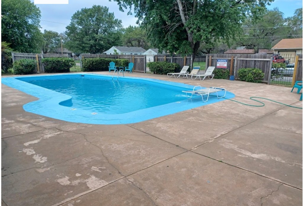 a swimming pool in a backyard with chairs and a fence