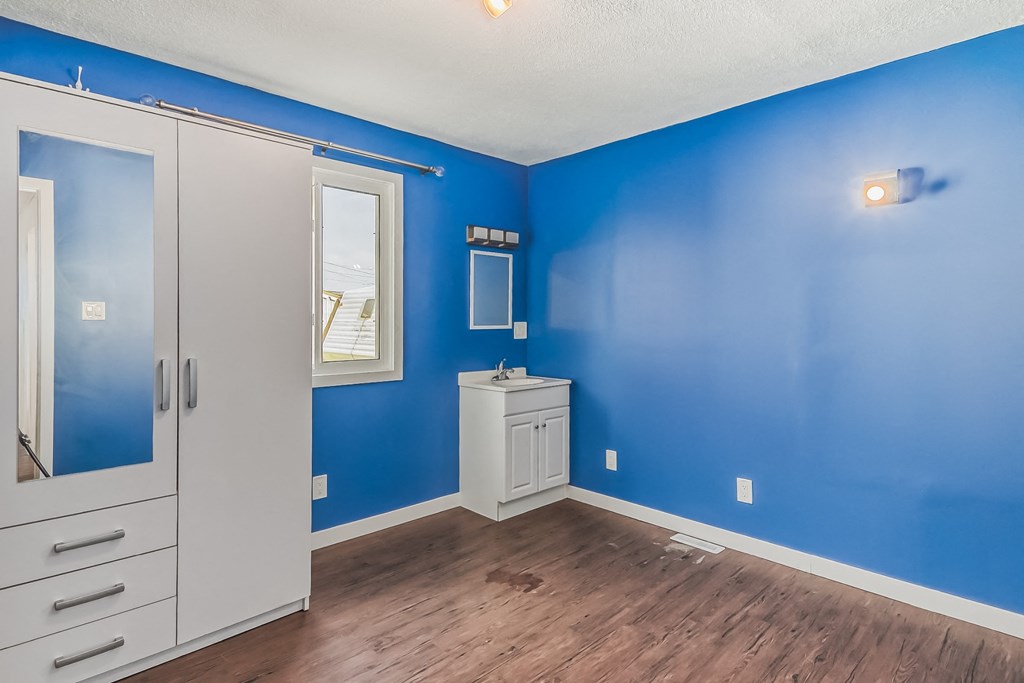 an empty room with blue walls and a bathroom with a white door