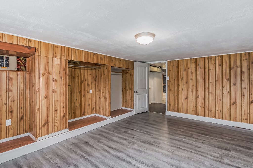 the living room has wood paneling on the walls and a wood floor