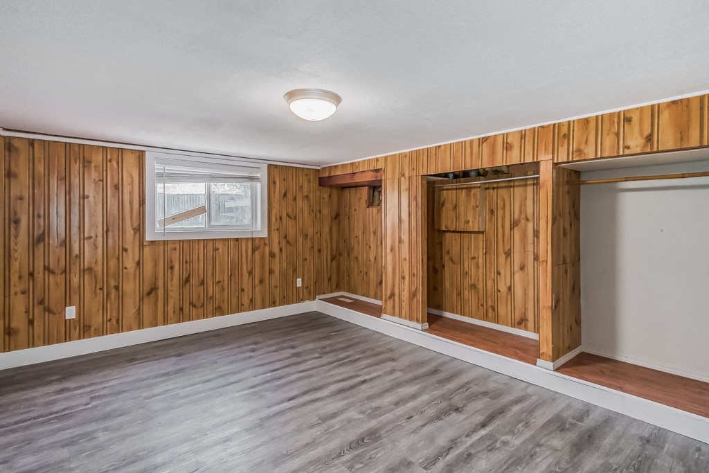 an empty living room with wood paneling and a door to a closet
