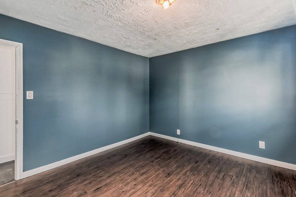 an empty room with blue walls and a white ceiling and wooden floors