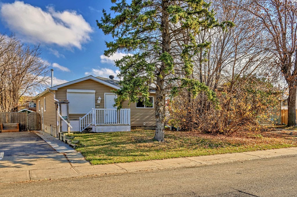 a yellow house with a porch and a tree in front of it