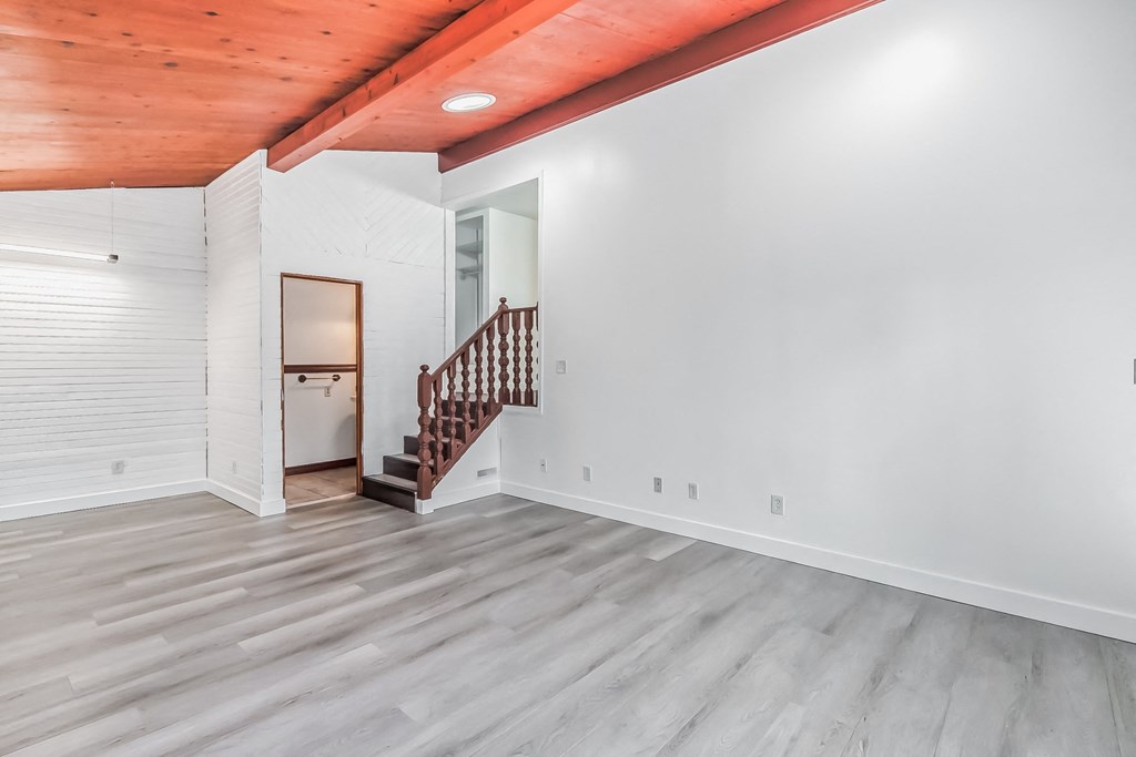 a renovated living room with white walls and a wooden staircase