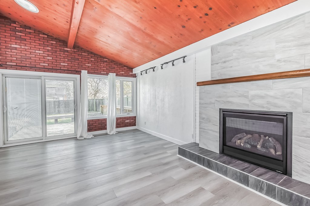 a living room with a brick fireplace and a wooden ceiling