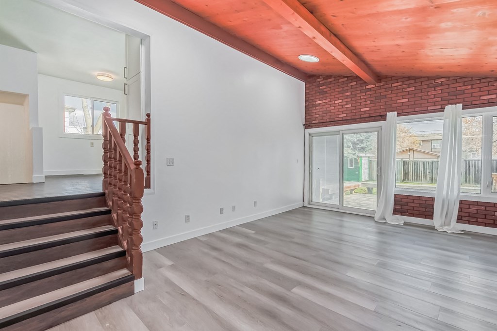 the living room of a house with a staircase and a brick wall
