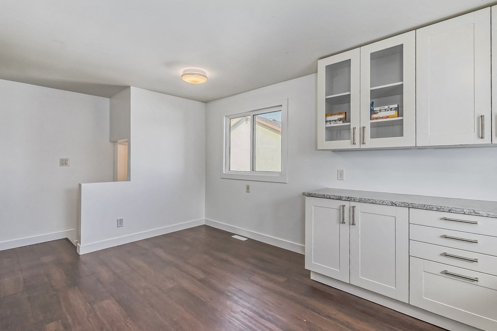 an empty kitchen with white cabinets and a wood floor