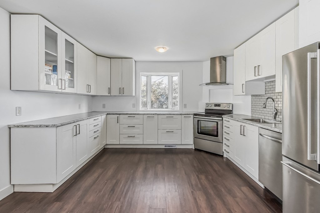 a large kitchen with white cabinets and stainless steel appliances