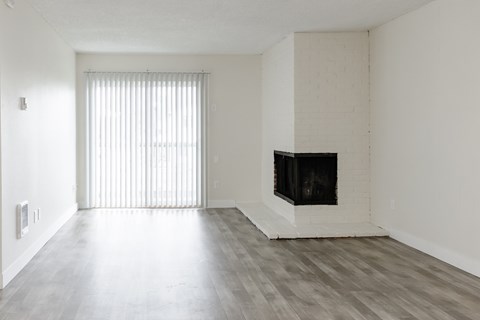 A living room with a fireplace and a window with blinds.