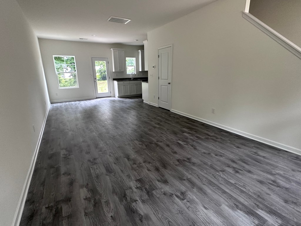 an empty living room with white walls and a wooden floor