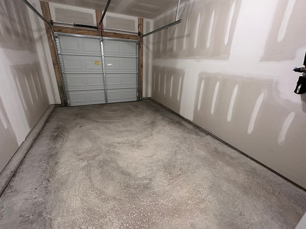 a garage with white walls and a cement floor and two doors