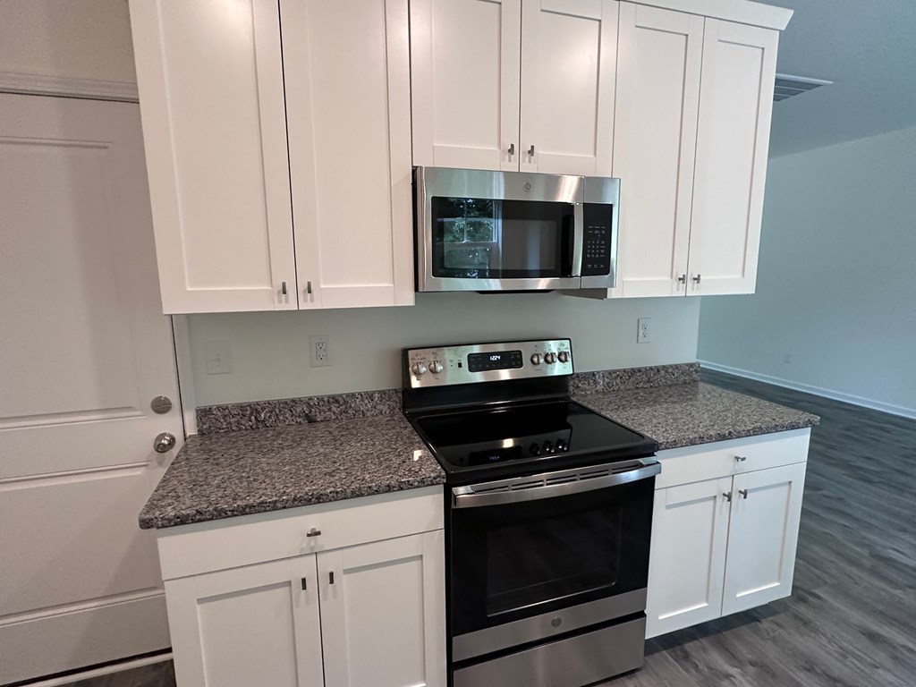 a kitchen with white cabinets and a stove and a microwave