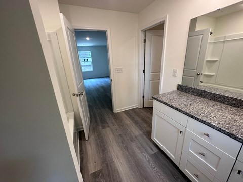 a kitchen with white cabinets and a hallway with a door to a bedroom