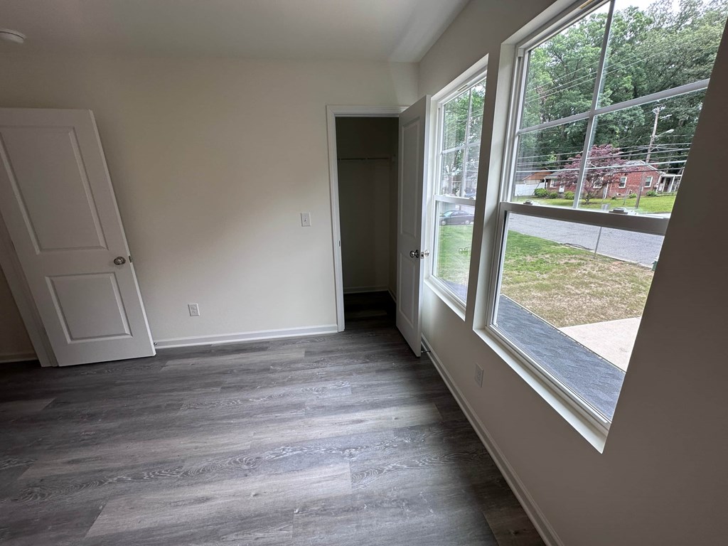 a bedroom with a large window and wooden floors