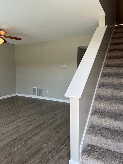 a living room with stairs and a carpeted staircase